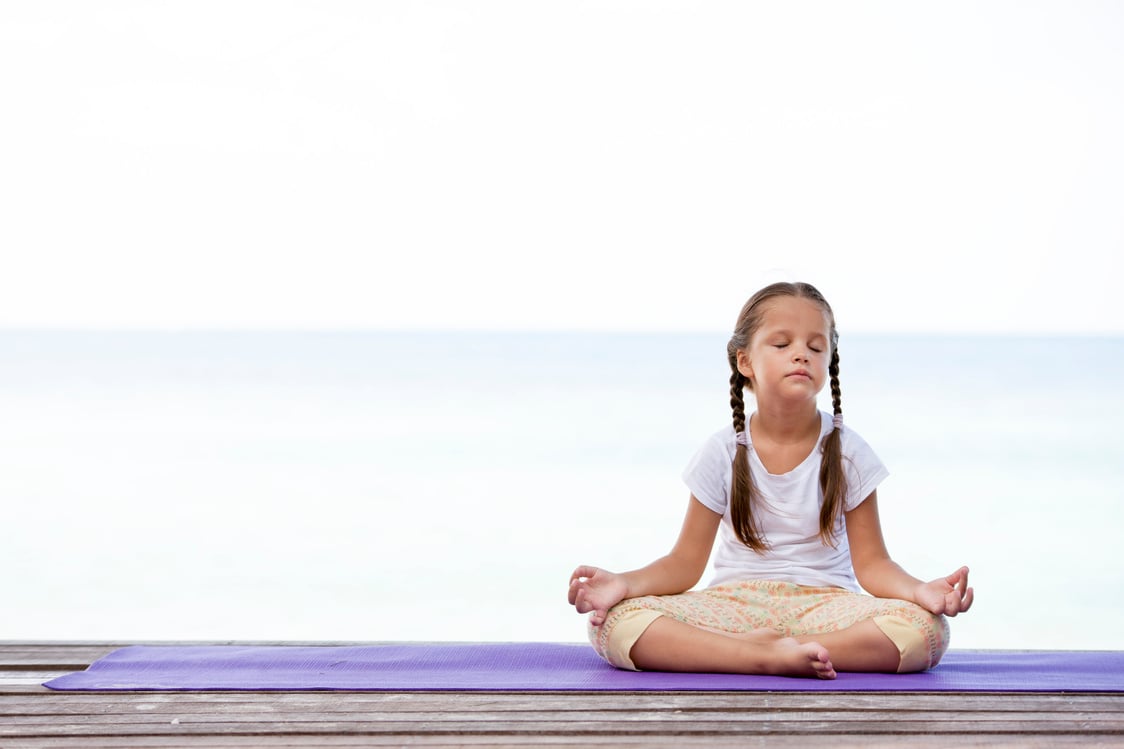 Child Meditating on Platform Outdoors